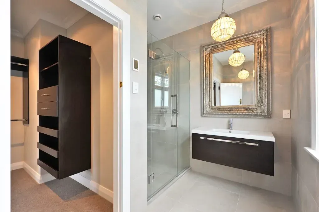 Completed bathroom with custom storage, tiled shower and wall-mounted vanity
