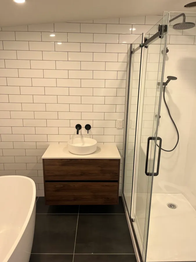 Tiled shower renovation with black fittings and glass enclosure